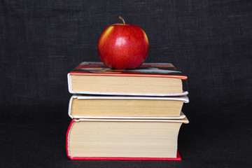 Pile stack of books with red apple on top, back to school concept, education concept, copy text space, black background