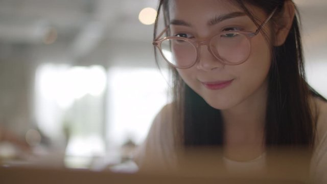 Freelance Asian women working on laptop at office. Young Asia business Girl using the computer for trade, send email, digital work on the internet on table at workplace concept. Slow motion.