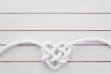 Heart shaped knot on white wooden background