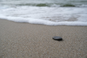 Fototapeta na wymiar The dark stone on the sand
