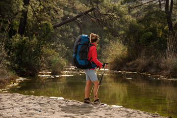 Female traveller standing by forest river shore