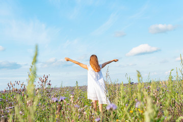 girl in a field of buckwheat. girl in white dress from back. girl in the harvest field