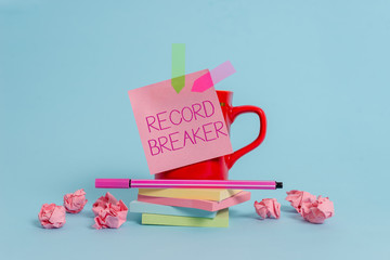 Writing note showing Record Breaker. Business concept for someone or something that beats previous best result Coffee cup pen note banners stacked pads paper balls pastel background