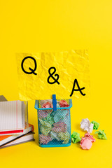 Conceptual hand writing showing Q And A. Concept meaning defined as questions being asked and answers Trash bin crumpled paper clothespin office supplies yellow