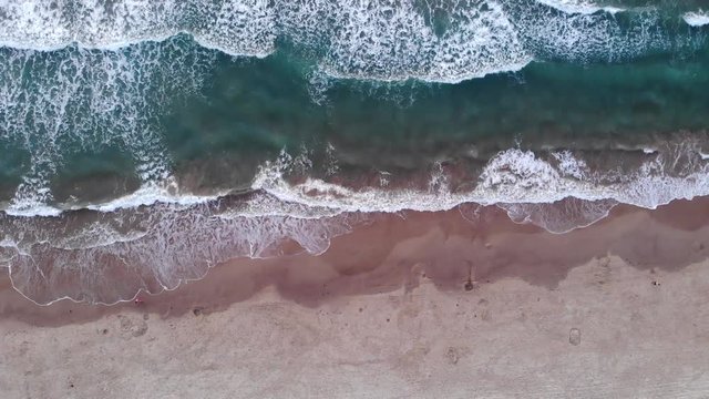 Aerial Top View of Ocean Waves and Beach During the Early Monring
