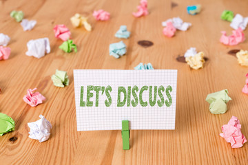 Conceptual hand writing showing Let S Discuss. Concept meaning asking someone to talk about something with demonstrating or showing Colored crumpled papers wooden floor background clothespin