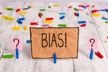 Conceptual hand writing showing Bias. Concept meaning inclination or prejudice for or against one demonstrating group Crumbling sheet with paper clips placed on the wooden table - obrazy, fototapety, plakaty