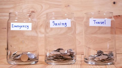Time lapse save money coin with separate expenses for emergency, saving and travel into the glass on wood background (Thai currency, THB coin)
