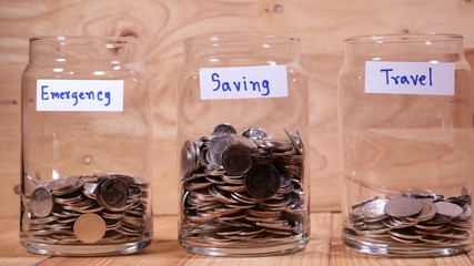 Time lapse save money coin with separate expenses for emergency, saving and travel into the glass on wood background (Thai currency, THB coin)