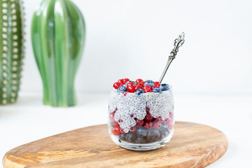 Chia seed pudding with blueberries, red currant berries and coconut flakes in a glass