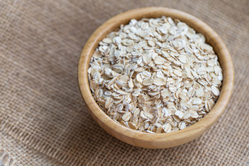 Uncooked oatmeal or oat flakes in a wooden bowl