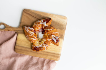 Strawberry and Sweet Cheese Danish with Icing Drizzle on Wooden Serving Board, Pink Napkin, Fruit Pastry Flat Lay on White Background