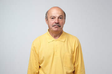 Sad upset mature hispanic guy in yellow pullover looking with guilt and sadness. Studio shot