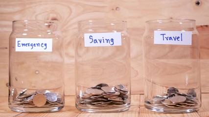 Time lapse save money coin with separate expenses for emergency, saving and travel into the glass on wood background (Thai currency, THB coin)