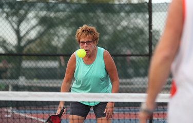 A senior woman plays pickleball