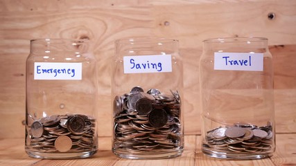 Time lapse save money coin with separate expenses for emergency, saving and travel into the glass on wood background (Thai currency, THB coin)