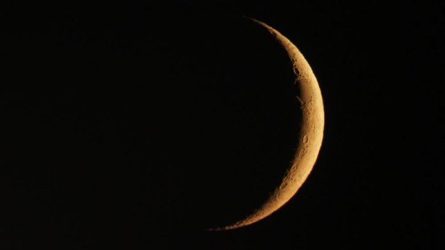 Waxing crescent moon seen with telescope in hot summer night, moon movement and air turbulence visible