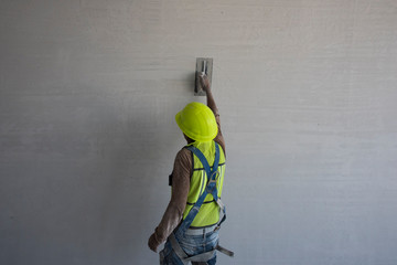 Albañil puliendo con cemento la pared de una obra en construcción
