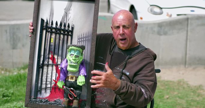 Disabled painter artist in the wheelchair shows his 3D painting to the tourists at Venice Beach in Los Angeles, California, 4K