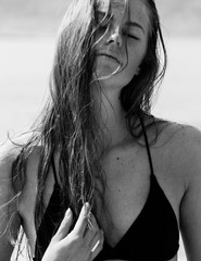 Black and white photo of young beautiful girl posing on a beach with sand in black swimwear. Calm,...