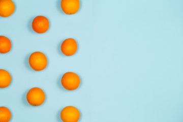 Oranges fruits pattern with oranges over a light blue background with large copy space.