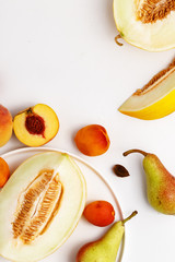 Sliced ripe juicy melon, apricots and pears on a white background. Top view.