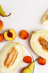 Sliced ripe juicy melon, apricots and pears on a white background. Top view.