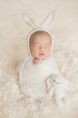 Adorable newborn baby sleeping in cozy room. Cute happy infant baby portrait with sleepy face in...