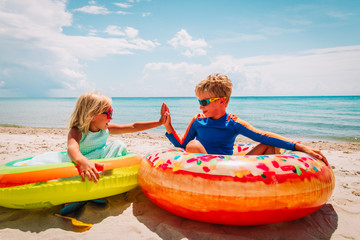 happy cute boy and girl play with floaties on beach