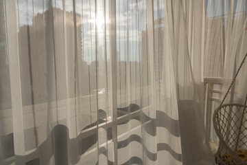 Looking at modern architectural light and shadow through translucent white gauze curtains on the balcony