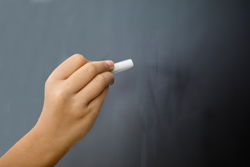 Hand of little girl writing on the empty blackboard