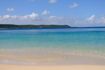 Tropical sandy beach in caribbean with an island on the horizon.