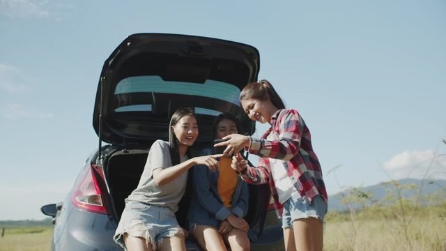 Asian teenager group is watching a picture on a mobile phone, Simultaneously while sitting At are trunk of the car In the summer time, In the midst of nature 