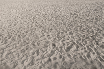 Close-up sand surface on a city beach at sunset.