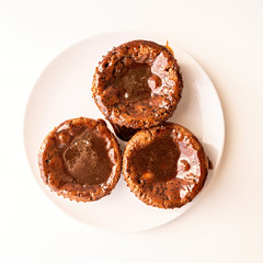 fresh homemade chocolate muffins with topping on white plate top view