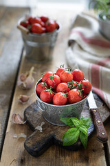 A group of red ripe cherry tomatoes as an ingredient to the sauce. On a wooden table