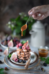 Chocolate waffles with figs, blackberries, raspberries and caramel sauce on top and mint