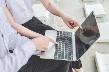 couple of friends young man and woman student in school uniform Thailand style using laptop in the city
