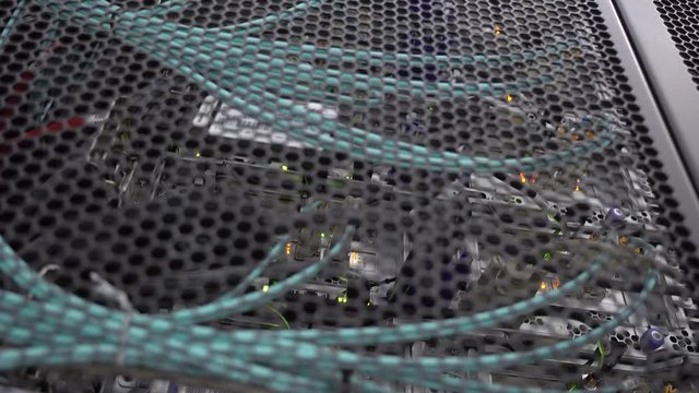 Server rack flashing led lights are in a modern data center are located behind an iron door with round openings.