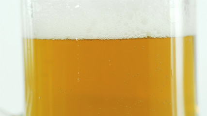 beer in a large class glass, light beer with thick white froth.