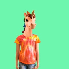 A girl with a unicorn head in a t-shirt in tie dye style on a green background. Contemporary art.