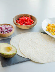 Ingredients for Mexican vegetarian tacos in bowls on light table, close-up