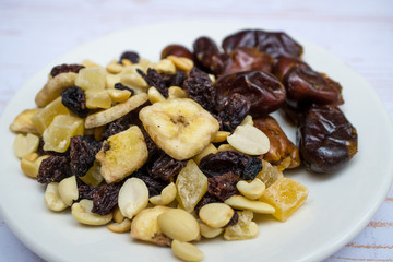 Dried fruit banana, date fruits, peanuts, pineapples etc on the plate. Close-up. Healthy food, healthy eating and healt care concept.