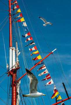 Colored signs and symbols of marine semaphore - signal nautical flags on the mast of the old sailing ship.