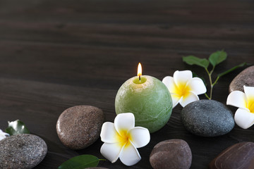 Composition with spa stones, flowers and candle on wooden background. Space for text