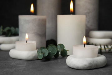 Fototapeta na wymiar Composition with burning candles, spa stones and eucalyptus on grey table