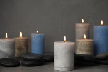 Obraz na płótnie Canvas Burning candles and spa stones on grey table