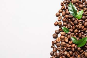 Fresh green coffee leaves and beans on light background, flat lay. Space for text