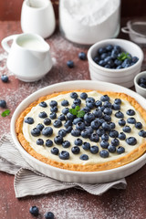 Blueberry tart with whipped cream on a wooden table