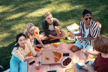 Students listening to their friend and eating pizza.